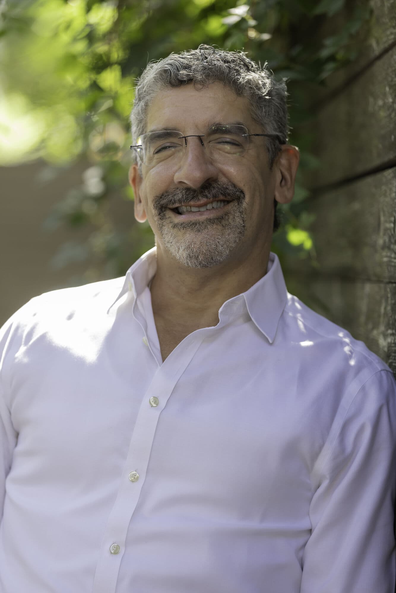 Dr. Jason Meisel smiling outdoors, sunlight through the trees behind him